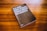 A book with a dark cover is placed on a wooden surface. The cover text reads 'Lea este libro si desea tomar buenas fotografías' by Henry Carroll. The background consists of a rich, warm wood grain texture.