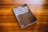 A book with a dark cover is placed on a wooden surface. The cover text reads 'Lea este libro si desea tomar buenas fotografías' by Henry Carroll. The background consists of a rich, warm wood grain texture.