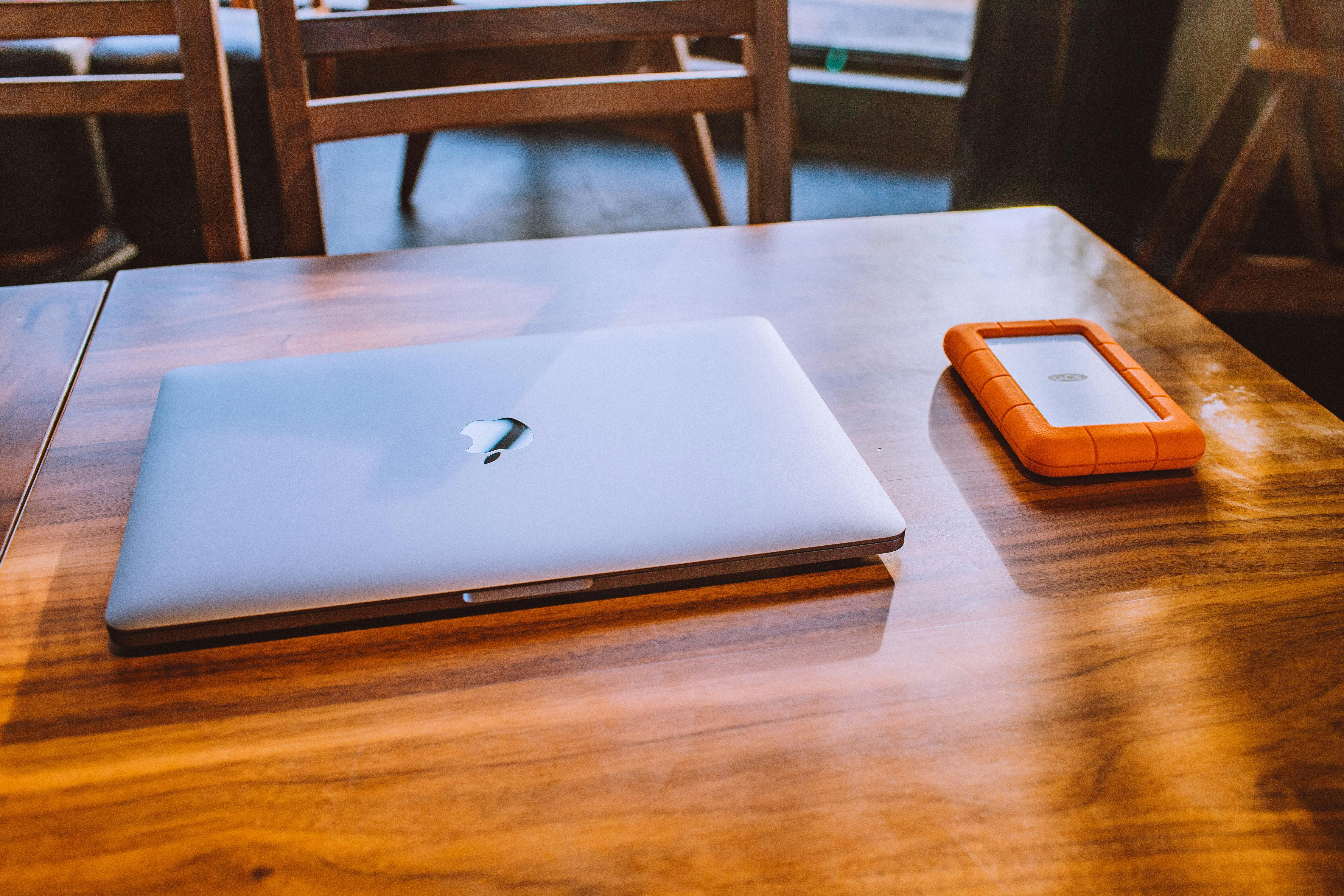 silver MacBook on brown wooden table