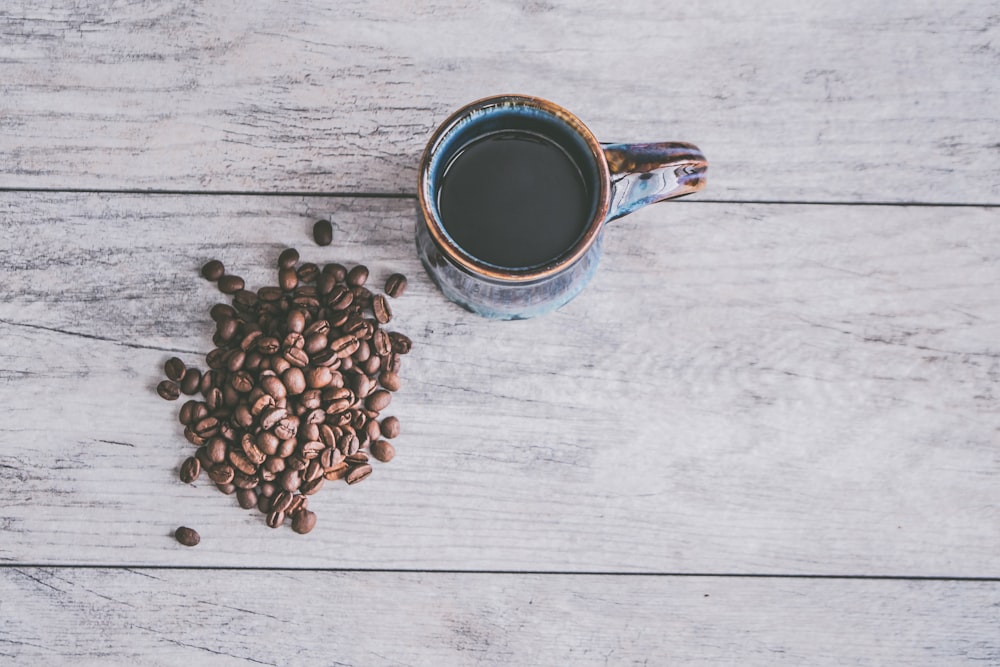 a cup of coffee next to a pile of coffee beans