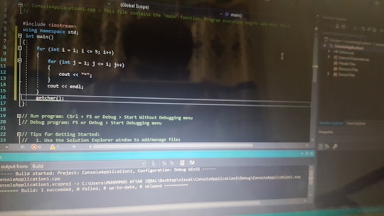 A computer screen displaying a code editor with a C++ program. The code includes a main function and nested for loops for printing stars. There are various sections of the interface visible, including a text editor with syntax highlighting, output panel showing build results, and project explorer on the side.