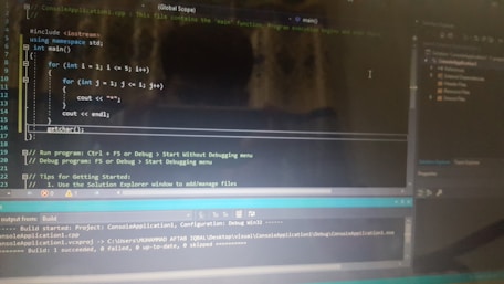 A computer screen displaying a code editor with a C++ program. The code includes a main function and nested for loops for printing stars. There are various sections of the interface visible, including a text editor with syntax highlighting, output panel showing build results, and project explorer on the side.