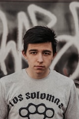 Young person wearing an oversized printed t-shirt against a graffiti wall