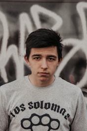 A young person wearing a sleek, modern slim-fit tee standing against a muted urban wall.