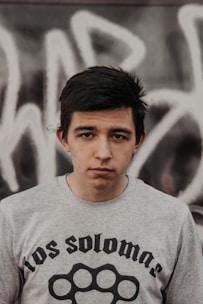 A young person wearing a sleek, modern slim-fit tee standing against a muted urban wall.