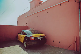 A sleek black taxi with yellow accents parked outside Arlanda Airport under a clear blue sky.