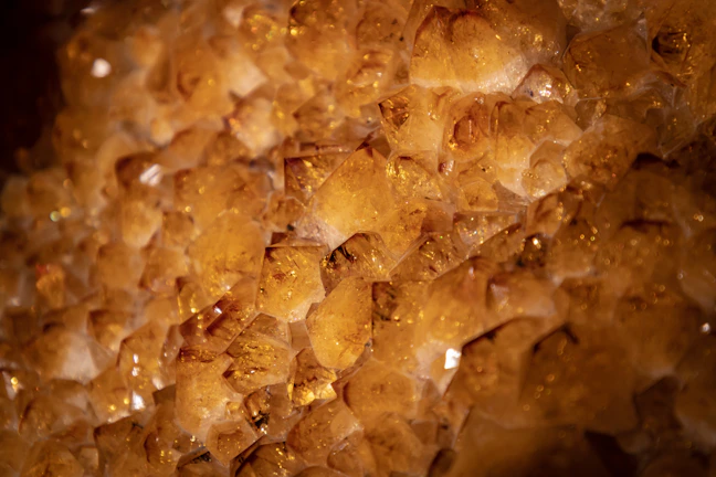 A vibrant citrine stone shining warmly against a dark fabric.