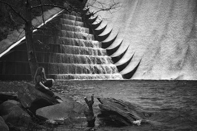 grayscale photo of woman sitting on rock