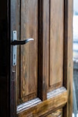 Maintenance technician inspecting a rustic wooden door in natural light.