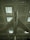 A vintage military jet airplane is suspended from the ceiling of a large indoor exhibition space. The aircraft has a sleek silver body with marked symbols on each wing, and it is viewed from below, emphasizing its aerodynamic shape and design features.