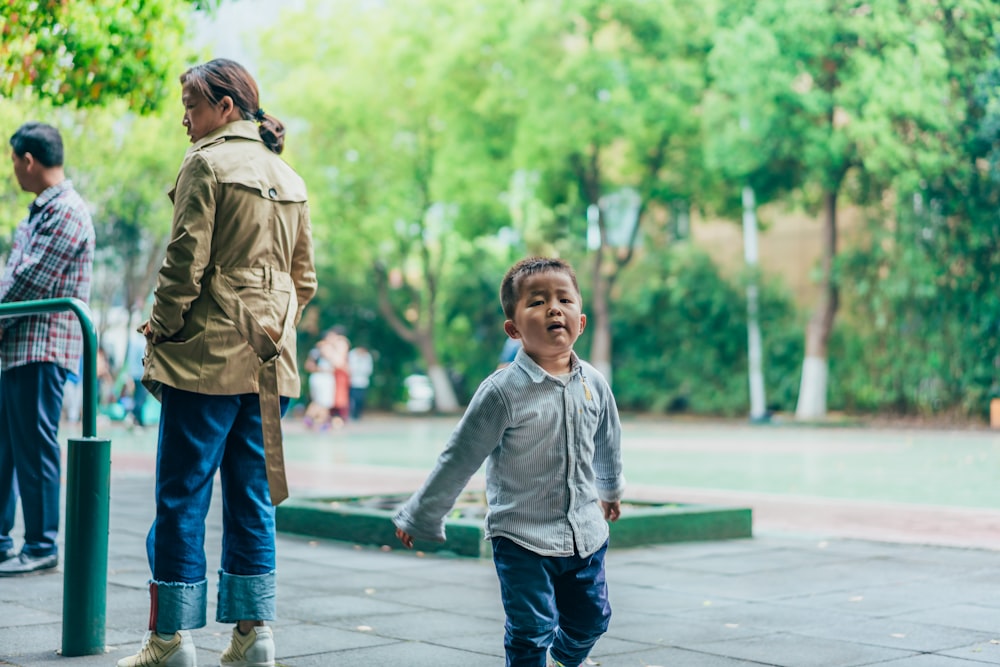 a little boy is walking down the sidewalk