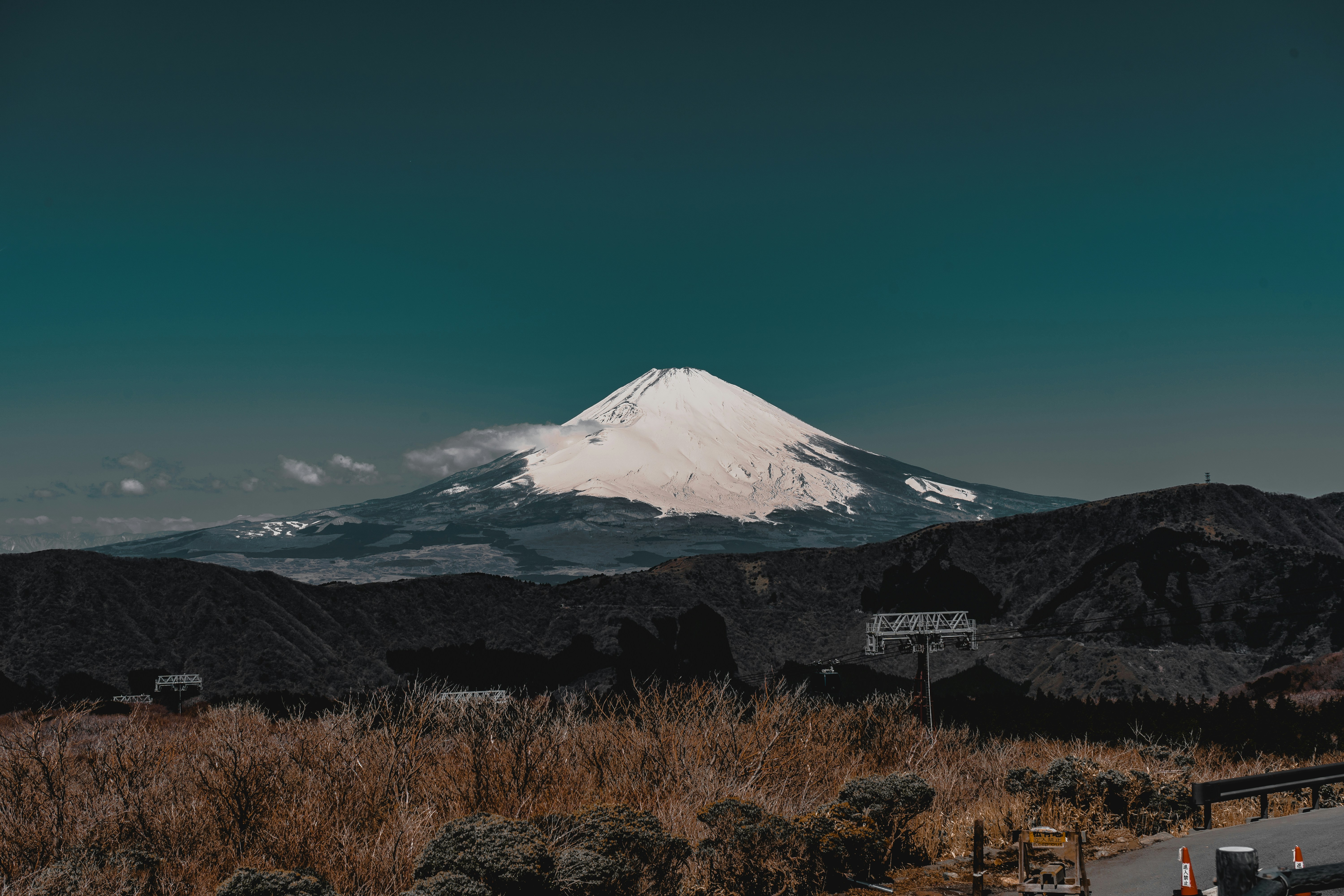 Mount Fuji with cherry blossom trees in foreground, dark atmospheric sky, moody low-key lighting, deep shadows