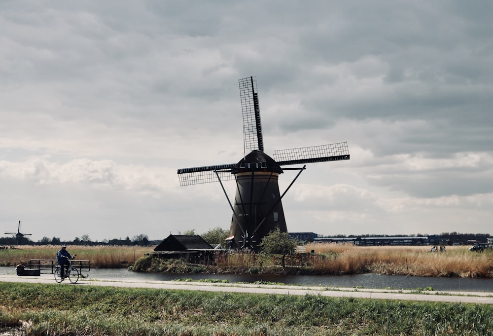 brown windmill near body of water