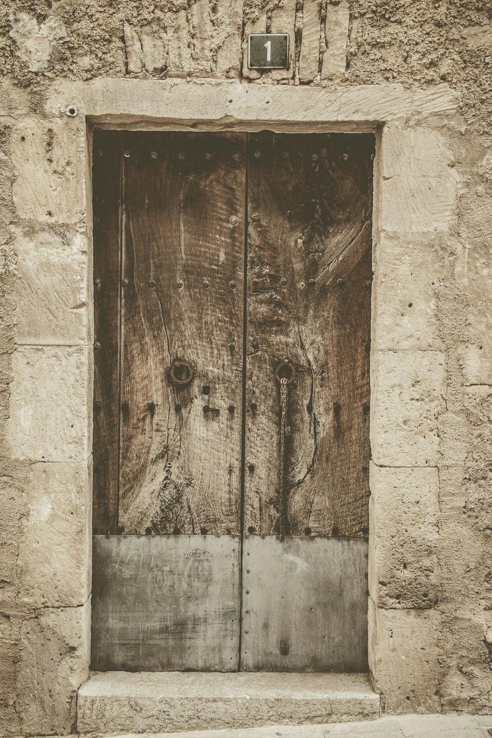 a wooden door with a metal handle on a stone building