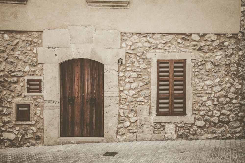 a stone building with a wooden door and shutters