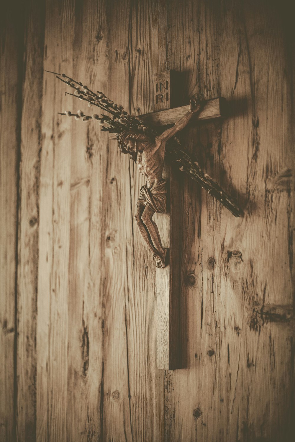 a cross on a wooden wall with chains hanging from it