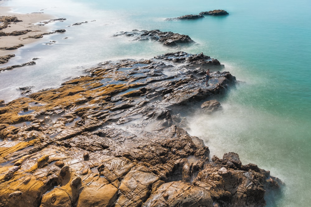 an aerial view of a rocky beach with blue water