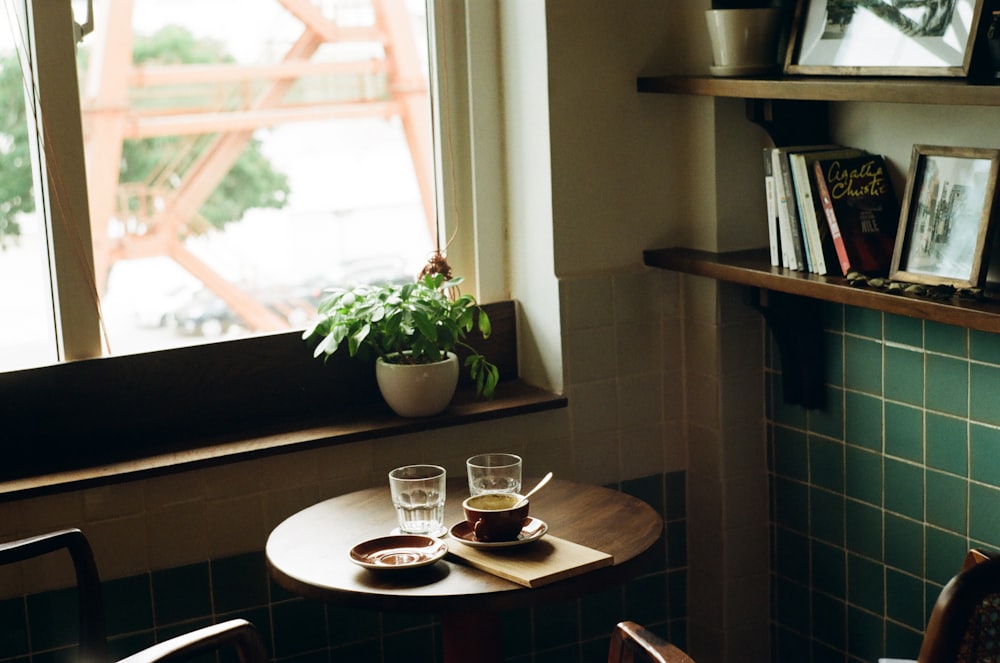 a table with two cups of coffee and a potted plant
