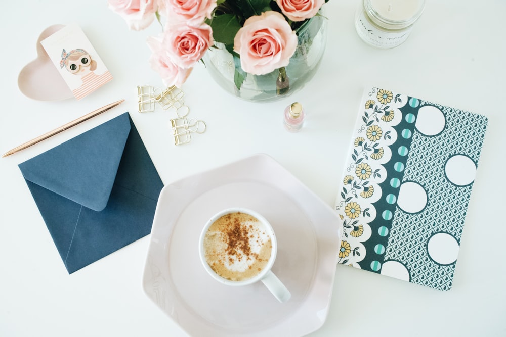 a cup of coffee sitting on top of a white plate