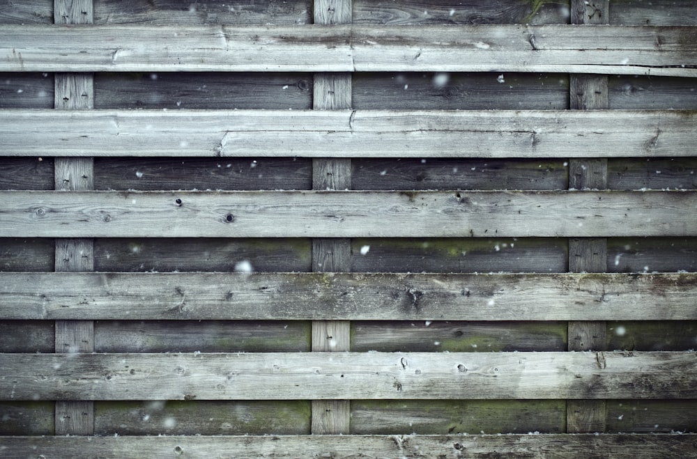 a wooden fence with snow falling on it