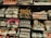 Several stacks of folded band t-shirts are displayed on shelves, featuring various music groups and artists such as Madness, Nirvana, Morrissey, Oasis, and others. Each stack is neatly arranged and some shirts have visible price tags.