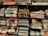 Several stacks of folded band t-shirts are displayed on shelves, featuring various music groups and artists such as Madness, Nirvana, Morrissey, Oasis, and others. Each stack is neatly arranged and some shirts have visible price tags.