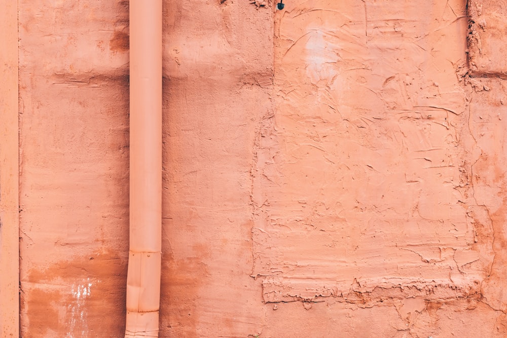 Ein roter Hydrant, der neben einer rosa Wand sitzt