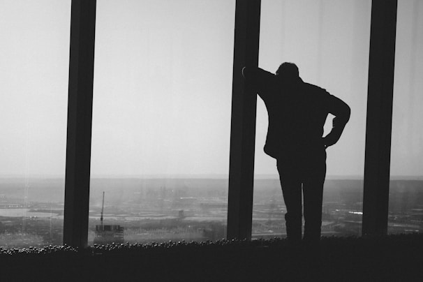 silhouette photography of person leaning on post