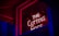 A brightly lit neon sign with the words 'THE CUTTING EDGE' is displayed inside a window, creating a striking contrast against the dark surroundings. The neon light casts a red and pink glow, which reflects on the glass pane and the structures nearby.