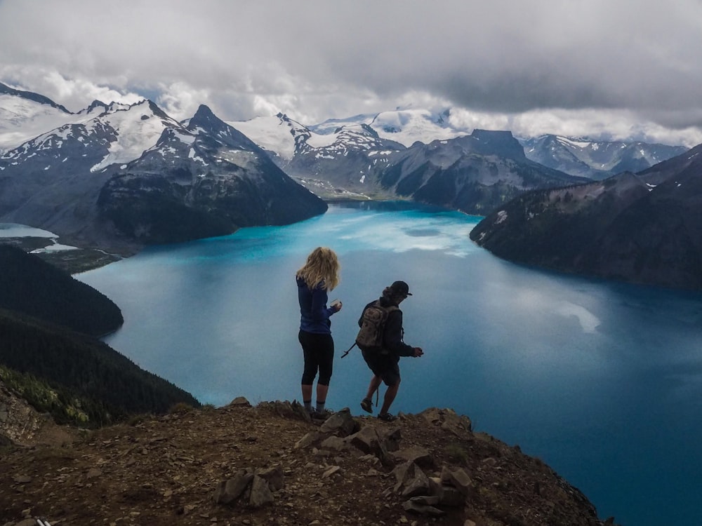 two women standing on cliff near body of water