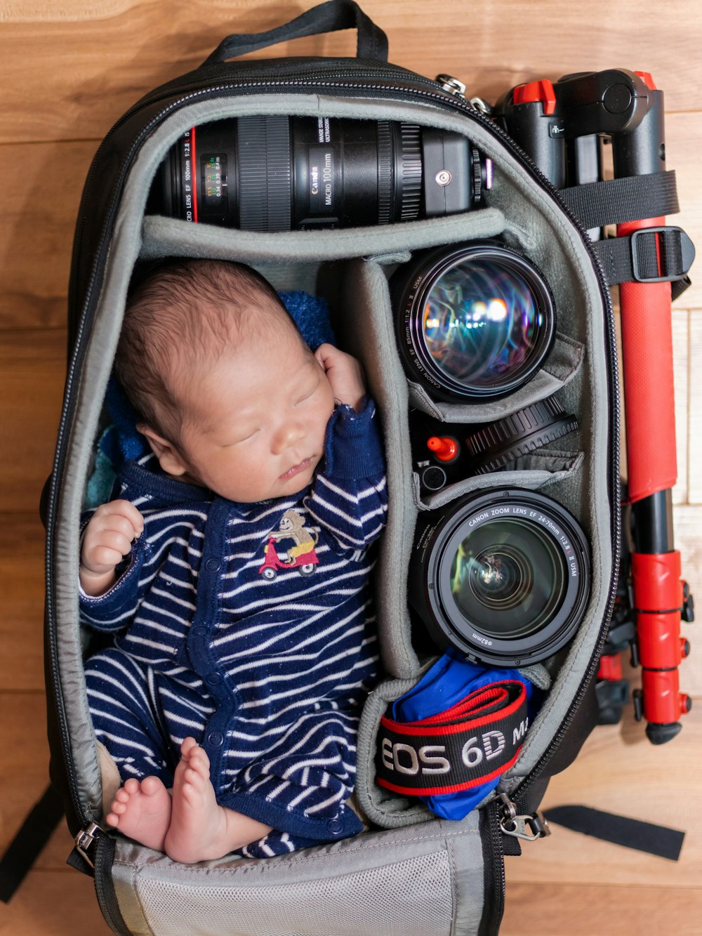 sleeping baby in a camera bag with camera lenses