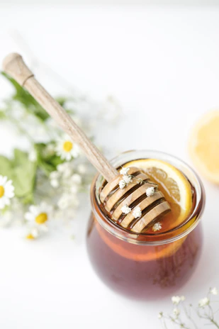 Honey jar with a wooden dipper surrounded by blooming saffron flowers.
