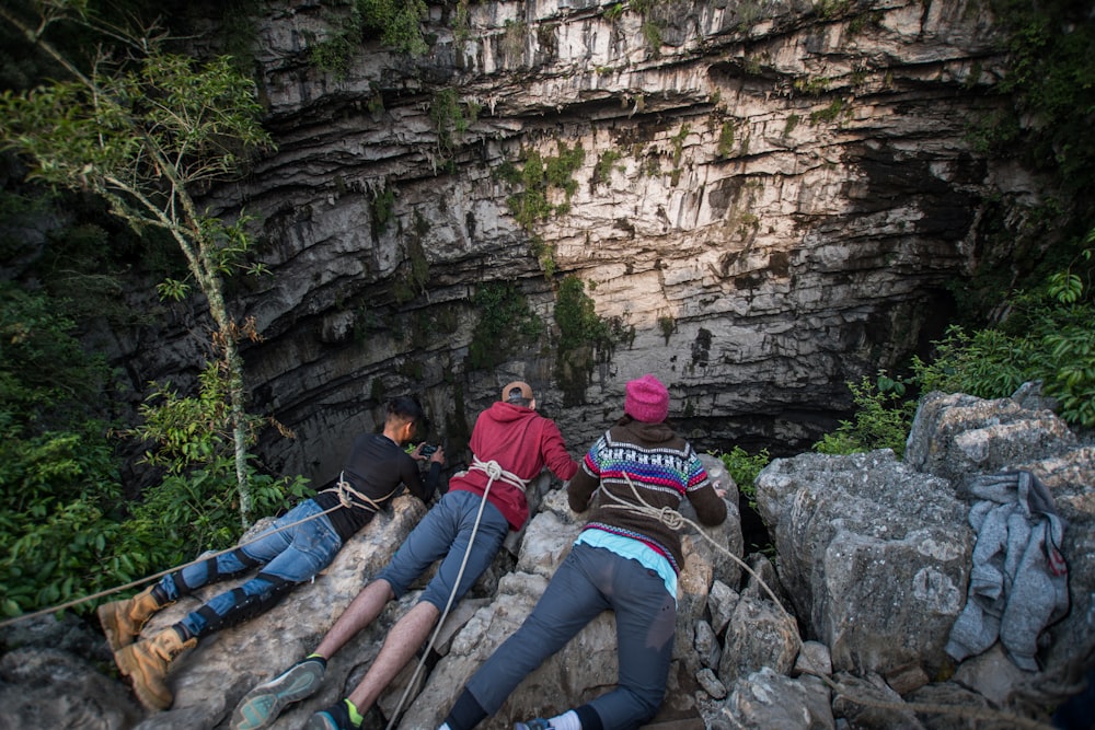 three people lying on boulders