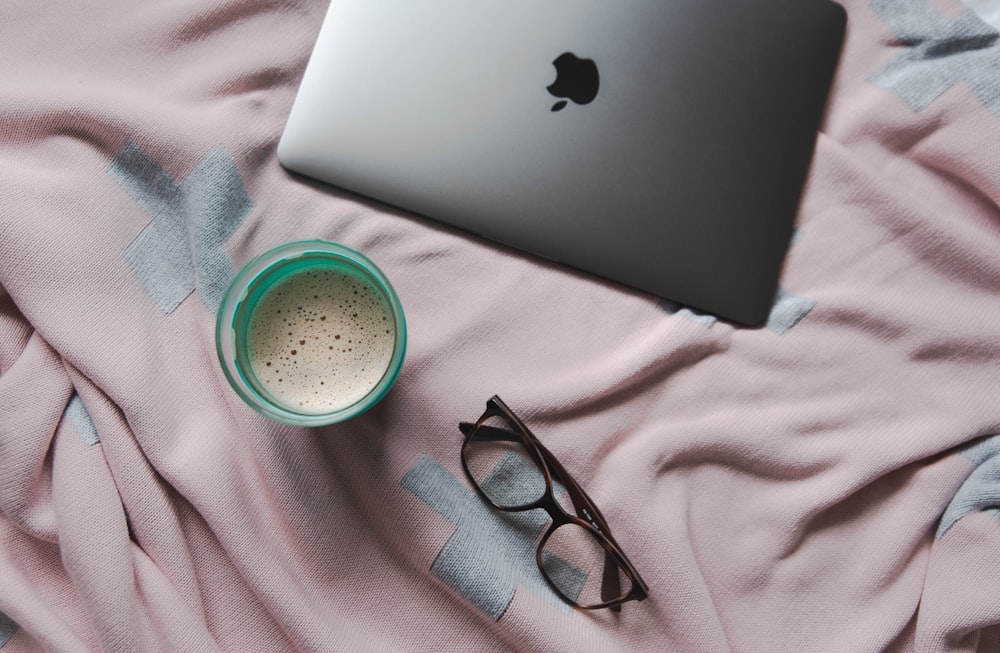 MacBook silver and black framed eyeglasses on top of brown textile