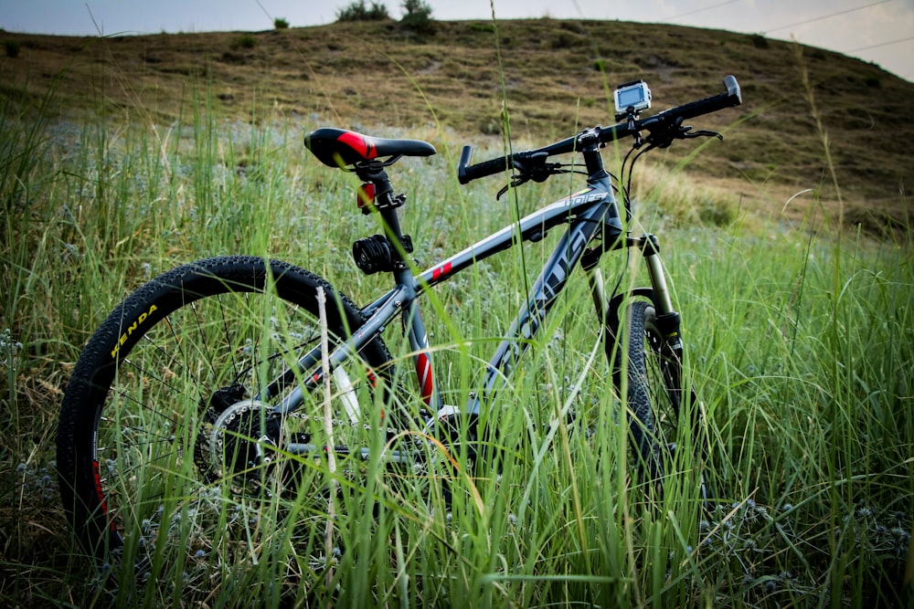 Bicicleta cinza e preta estacionada perto da grama na colina