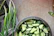 Close-up of perfectly sliced cucumbers and carrots on a kitchen counter next to the slicer.