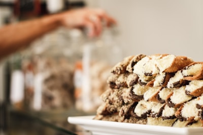 Close-up of a freshly filled cannolo with creamy ricotta and pistachio dusting, held by a smiling artisan.