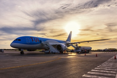 Airline cargo plane fueling up on runway with sunrise background.