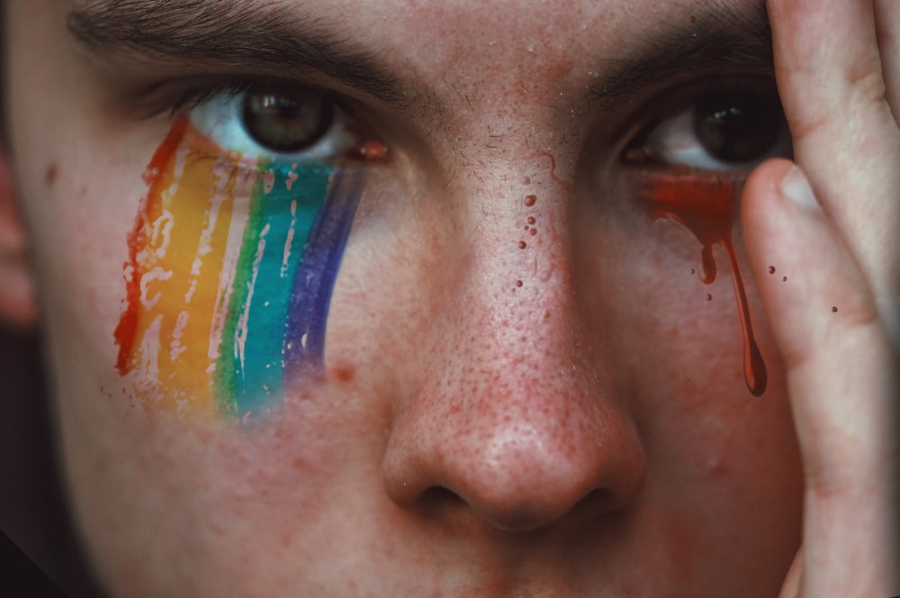 Fotografía de primer plano de una persona con sombra de ojos de arco iris