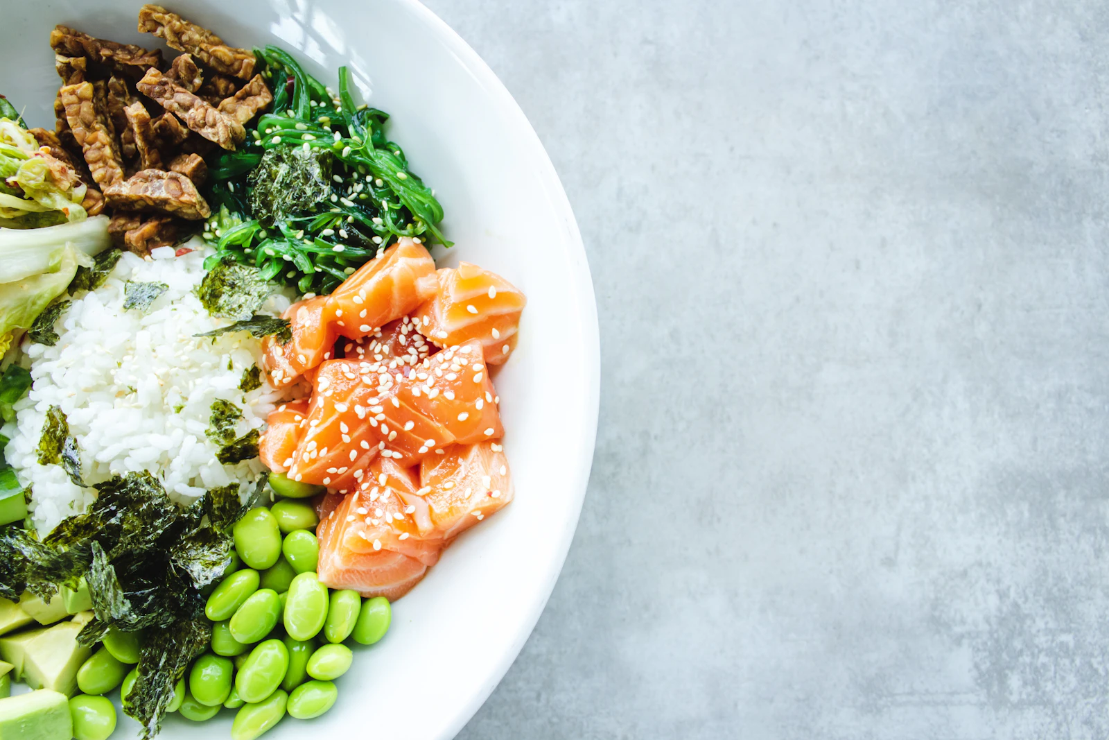 Bol de riz garni de dés de saumon, edamame, algues et graines de sésame