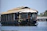 A cozy houseboat deck with traditional Kashmiri cushions overlooking Dal Lake at sunrise.