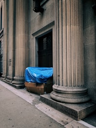 a blue tarp covering a piece of luggage on the side of a building