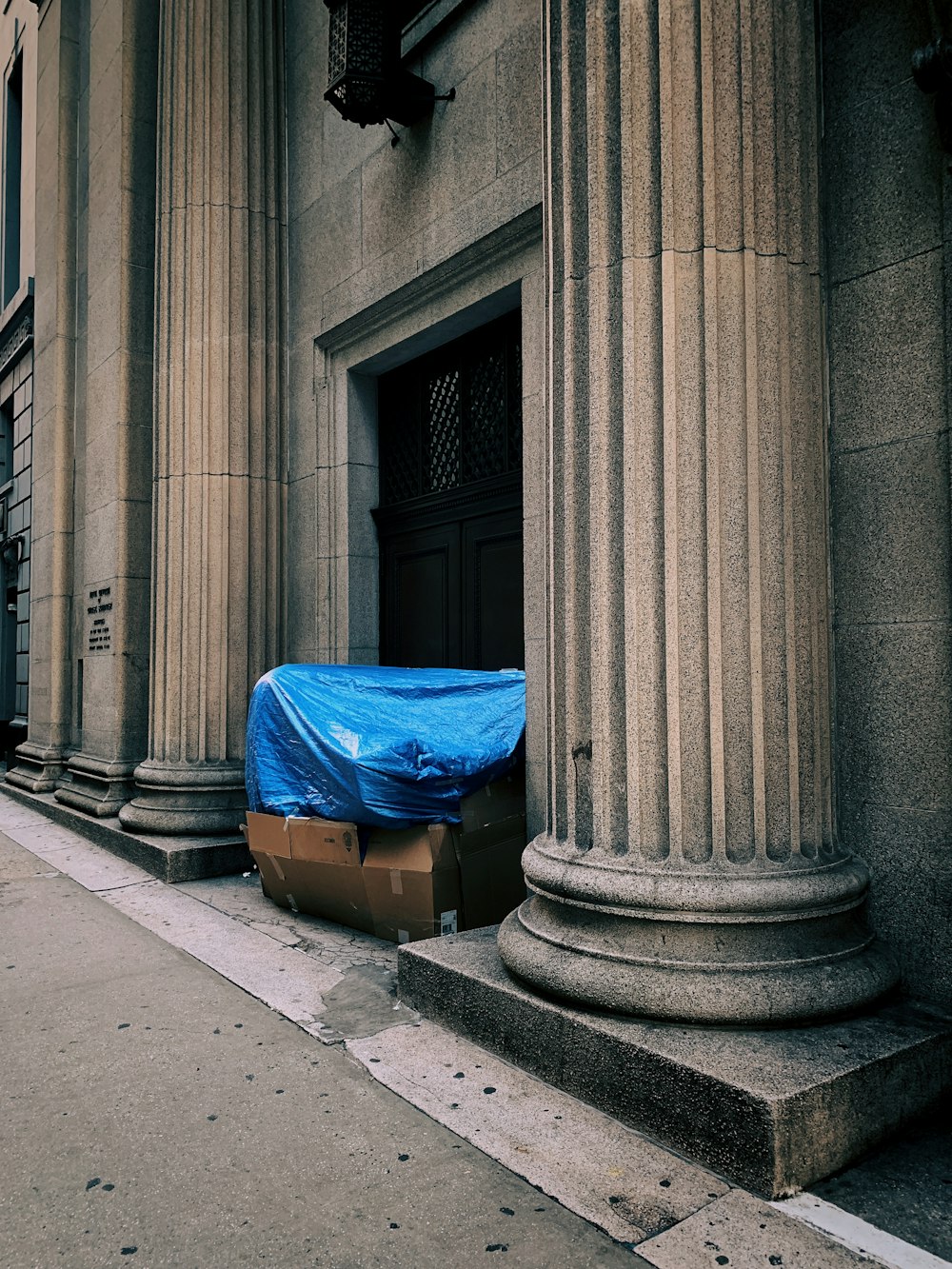 a blue tarp covering a piece of luggage on the side of a building