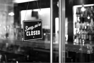 sorry, we're closed signboard hanging on glass door