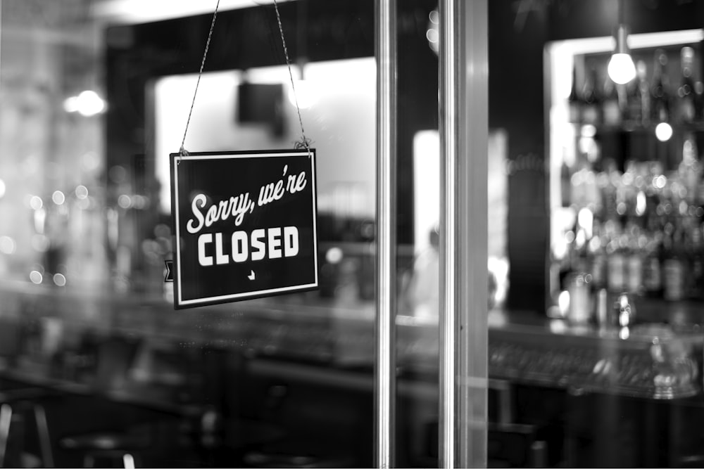 sorry, we're closed signboard hanging on glass door