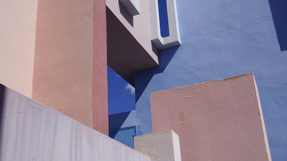 a blue and pink building with a clock on it's side