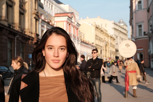 A candid photo of Nina Demushkina smiling warmly with a backdrop of a bustling city street during golden hour.