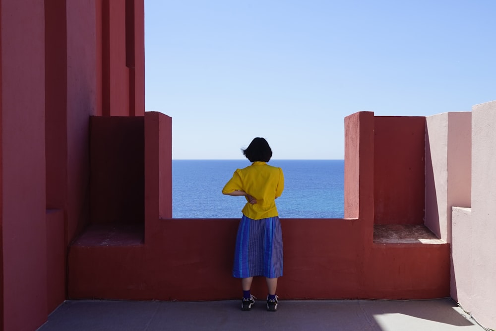 person standing on high deck facing body of water