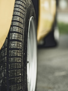 Close-up of a used truck tire with visible tread patterns in a yellow and black themed workshop.