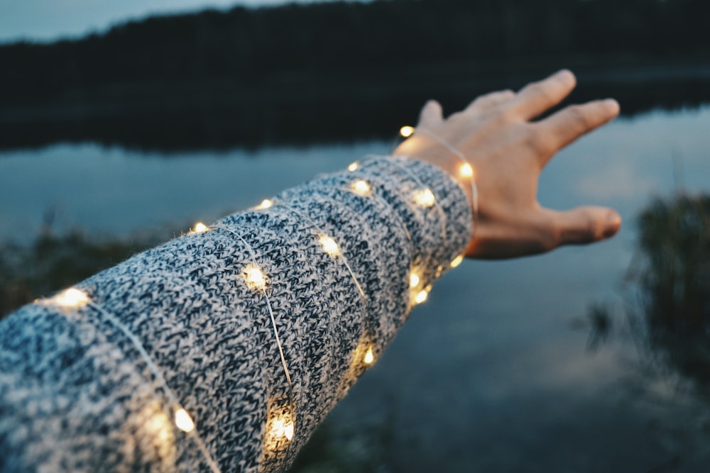 lighted yellow string lights coated on person's left arm